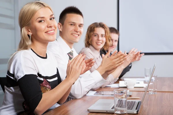 Portrait of successful applauding young people sitting in line — Stock Photo, Image