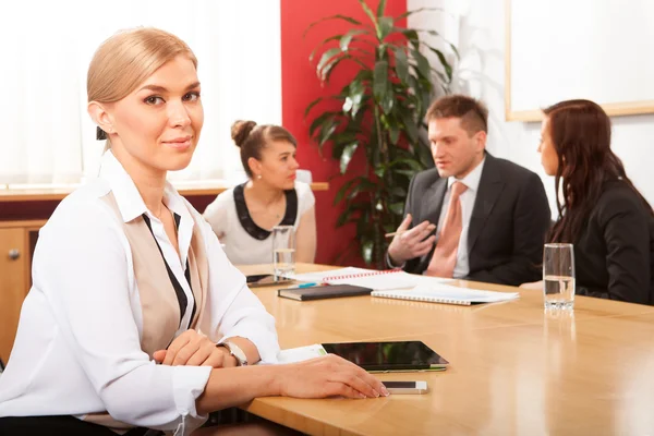 Happy businesswoman with colleagues in background — Stock Photo, Image