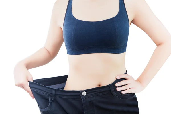 Close-up van slanke taille van jonge vrouw in grote spijkerbroek tonen van succesvolle gewichtsverlies, geïsoleerd op een witte achtergrond, dieet concept Stockfoto