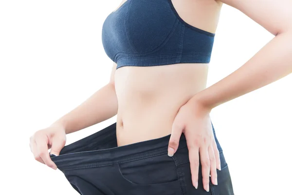 Close-up van slanke taille van jonge vrouw in grote spijkerbroek tonen van succesvolle gewichtsverlies, geïsoleerd op een witte achtergrond, dieet concept Rechtenvrije Stockfoto's