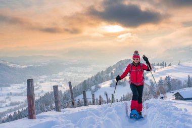 Avusturya, Vorarlberg, Bregenzerwald manzaralı Oberstaufen yakınlarındaki Allgaeu Alplerinde kar ayakkabısı giyen son sınıf öğrencisi hoş bir kadın.