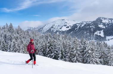 Allgau Alpleri, Bavyera, Almanya 'da kar altında kar ayakkabısı giyen güzel ve aktif bir kadın.