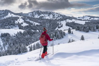 Allgau Alpleri, Bavyera, Almanya 'da kar altında kar ayakkabısı giyen güzel ve aktif bir kadın.