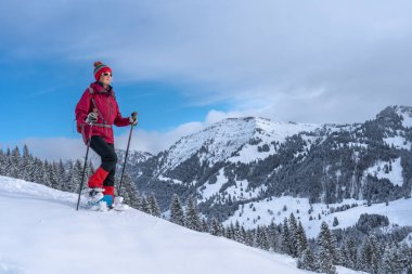 Allgau Alpleri, Bavyera, Almanya 'da kar altında kar ayakkabısı giyen güzel ve aktif bir kadın.