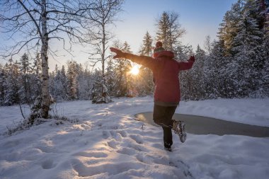 Allgaeu Alpleri, Bavyera, Almanya 'da gün batımında sakin bir kış manzarasında Neşe' den atlayan hoş bir kadın.