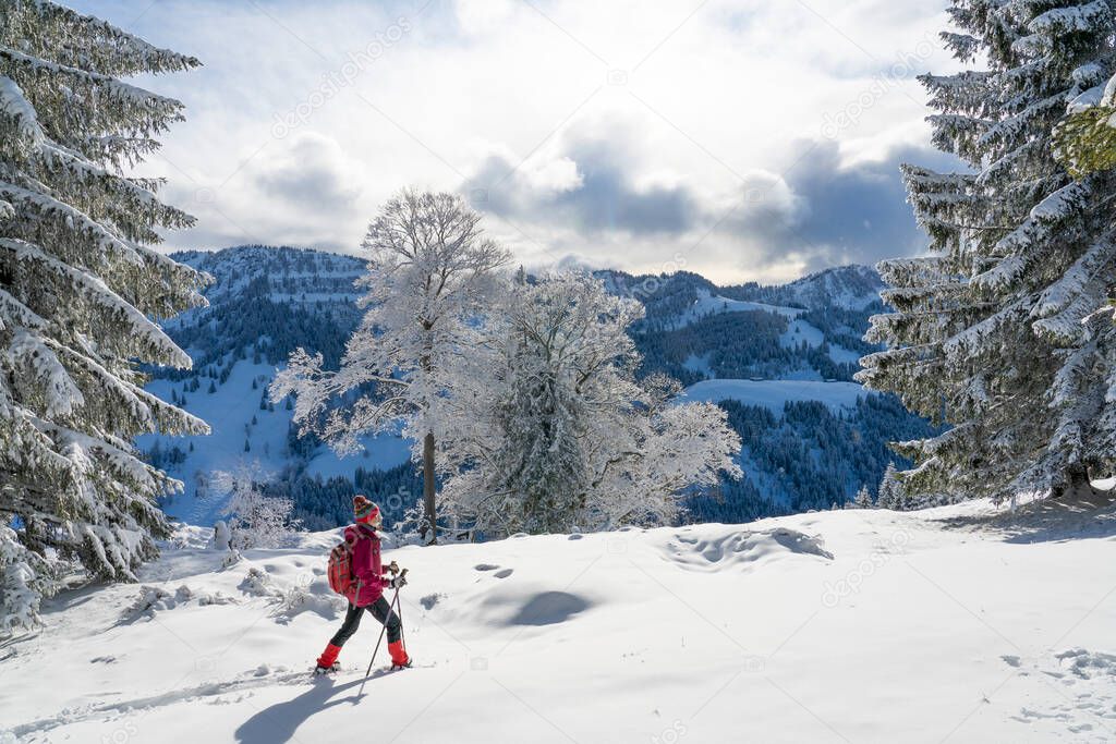 nice and active  woman snowshoeing in deep powder snow in the Allgau alps, Bavaria, Germany