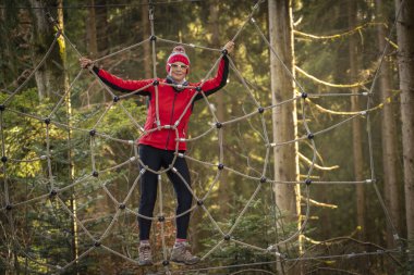 Ormanda dev bir casus ağına tırmanan mutlu, hoş, yaşlı bir kadın.