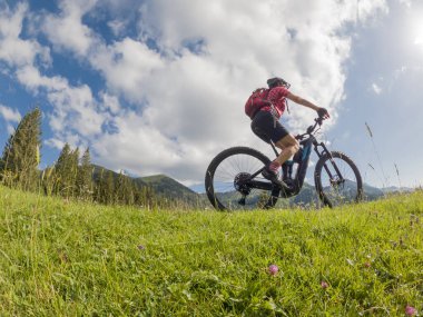 Almanya 'da Immenstadt, Algu, Bavyera yakınlarındaki Allgau Alplerinde elektrikli dağ bisikleti süren aktif son sınıf öğrencisi bir kadın.