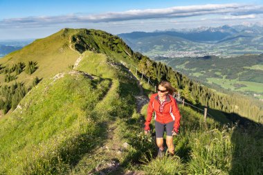 Almanya 'nın Bavyera, Immenstadt yakınlarındaki Allgau Alpleri' nde Nagelfluh zincirinin tepesinde sıcak şafak ışığında koşan aktif yaşlı kadın dağı