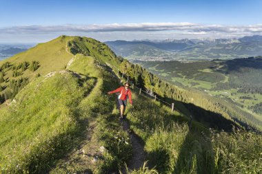 Almanya 'nın Bavyera, Immenstadt yakınlarındaki Allgau Alpleri' nde Nagelfluh zincirinin tepesinde sıcak şafak ışığında koşan aktif yaşlı kadın dağı