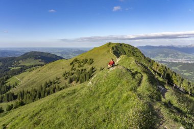 Almanya 'nın Bavyera, Immenstadt yakınlarındaki Allgau Alpleri' ndeki Nagelfluh zincirinin tepesinde sıcak şafak ışığında yürüyüş yaparken dinlenen yaşlı güzel bir kadın.