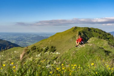 Almanya 'nın Bavyera, Immenstadt yakınlarındaki Allgau Alpleri' ndeki Nagelfluh zincirinin tepesinde sıcak şafak ışığında yürüyüş yaparken dinlenen yaşlı güzel bir kadın.