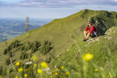 Almanya 'nın Bavyera, Immenstadt yakınlarındaki Allgau Alpleri' ndeki Nagelfluh zincirinin tepesinde sıcak şafak ışığında yürüyüş yaparken dinlenen yaşlı güzel bir kadın.