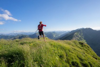 Almanya 'nın Bavyera, Immenstadt yakınlarındaki Allgau Alpleri' nde Nagelfluh zincirinin tepesinde sıcak şafak ışığında koşan aktif yaşlı kadın dağı