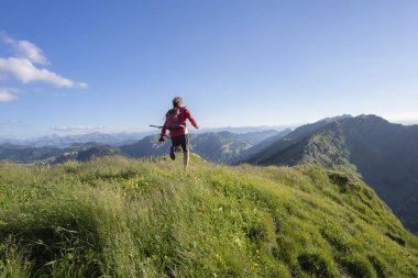 Almanya 'nın Bavyera, Immenstadt yakınlarındaki Allgau Alpleri' nde Nagelfluh zincirinin tepesinde sıcak şafak ışığında koşan aktif yaşlı kadın dağı