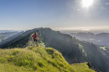Almanya 'nın Bavyera, Immenstadt yakınlarındaki Allgau Alpleri' ndeki Nagelfluh zincirinin tepesinde sıcak şafak ışığında yürüyüş yaparken dinlenen yaşlı güzel bir kadın.