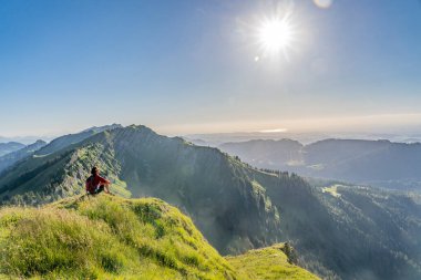 Almanya 'nın Bavyera, Immenstadt yakınlarındaki Allgau Alpleri' ndeki Nagelfluh zincirinin tepesinde sıcak şafak ışığında yürüyüş yaparken dinlenen yaşlı güzel bir kadın.