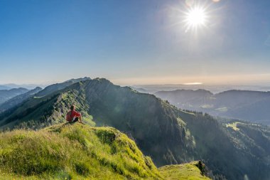 Almanya 'nın Bavyera, Immenstadt yakınlarındaki Allgau Alpleri' ndeki Nagelfluh zincirinin tepesinde sıcak şafak ışığında yürüyüş yaparken dinlenen yaşlı güzel bir kadın.