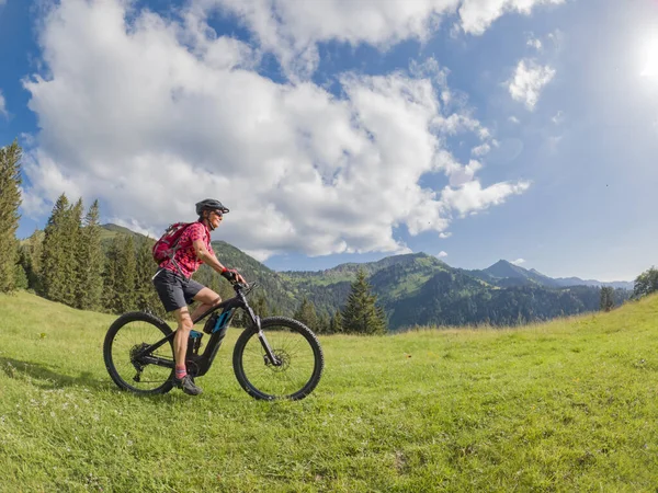 active senior woman riding her electric mountain bike in the Allgau Alps near city of Immenstadt, Algu, Bavaria, Germany