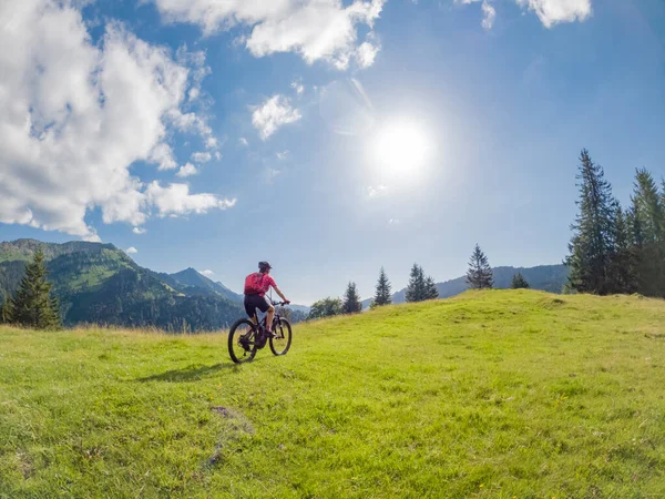 Almanya 'da Immenstadt, Algu, Bavyera yakınlarındaki Allgau Alplerinde elektrikli dağ bisikleti süren aktif son sınıf öğrencisi bir kadın.