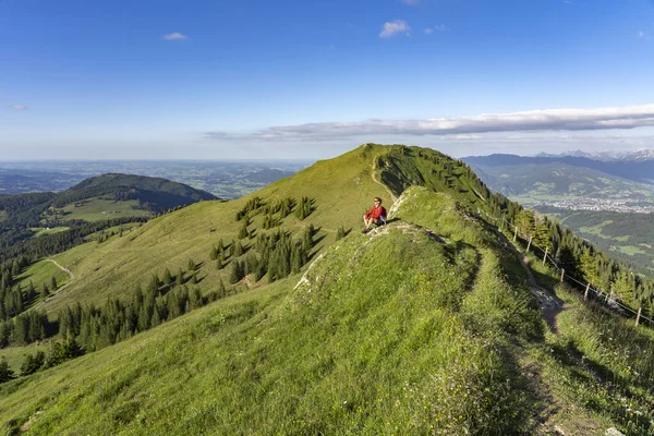 Almanya 'nın Bavyera, Immenstadt yakınlarındaki Allgau Alpleri' ndeki Nagelfluh zincirinin tepesinde sıcak şafak ışığında yürüyüş yaparken dinlenen yaşlı güzel bir kadın.