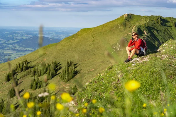 Almanya 'nın Bavyera, Immenstadt yakınlarındaki Allgau Alpleri' ndeki Nagelfluh zincirinin tepesinde sıcak şafak ışığında yürüyüş yaparken dinlenen yaşlı güzel bir kadın.