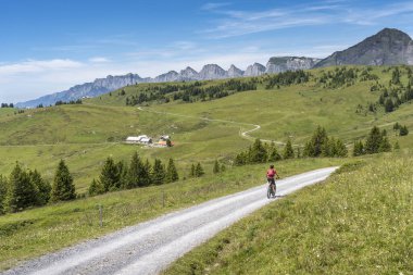 İsviçre, Canton St. Gallen 'de Churfirsten' in yedi zirvesinin altında elektrikli dağ bisikleti süren güzel aktif bir kadın.