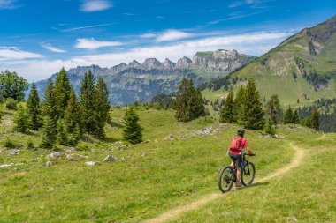 İsviçre, Canton St. Gallen 'de Churfirsten' in yedi zirvesinin altında elektrikli dağ bisikleti süren güzel aktif bir kadın.