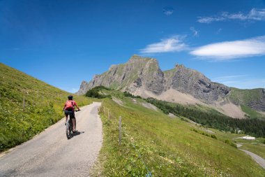 İsviçre, Canton St. Gallen 'de Churfirsten' in yedi zirvesinin altında elektrikli dağ bisikleti süren güzel aktif bir kadın.