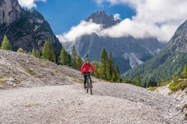Innichen, Tre cime Ulusal Parkı, Güney Tirol, İtalya yakınlarındaki Sexten Dolomites kasabasında elektrikli dağ bisikletine binen son sınıf güzel bir kadın. 