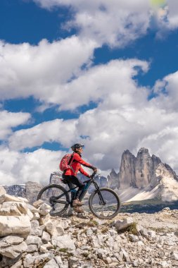 Güney Tyrol, İtalya 'daki Sexten Dolomitleri' nde ünlü Lavaredo Tepesi 'nin aşağısında elektrikli dağ bisikletine binen hoş yaşlı bir kadın.
