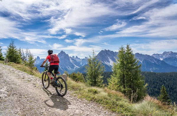 Toblach 'tan Marchkinkele' nin zirvesine kadar eski bir askeri yolda elektrikli dağ bisikleti süren hoş ve aktif bir kadın. Lavaredo, Güney Tirol 'ün üç tepesine muhteşem bir manzarası var., 