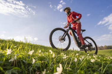 İlkbaharın başlarında Oberstaufen yakınlarındaki Allgau dağlarında elektrikli dağ bisikletine binen orta yaşlı güzel bir kadın.