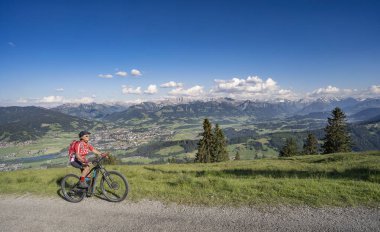 Iller Vadisi 'nin yukarısındaki Sonthofen ve Oberstdorf, Allgau Alps, Bavyera Almanya arasındaki dağlarda elektrikli dağ bisikletine binen son sınıf güzeli bir kadın.