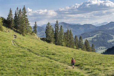 Sıcak şafak vakti yürüyüş yapan ve Almanya, Bavyera, Oberstdorf yakınlarındaki Allgau Alpleri 'nin muhteşem manzarasının tadını çıkaran son sınıf güzeli bir kadın.
