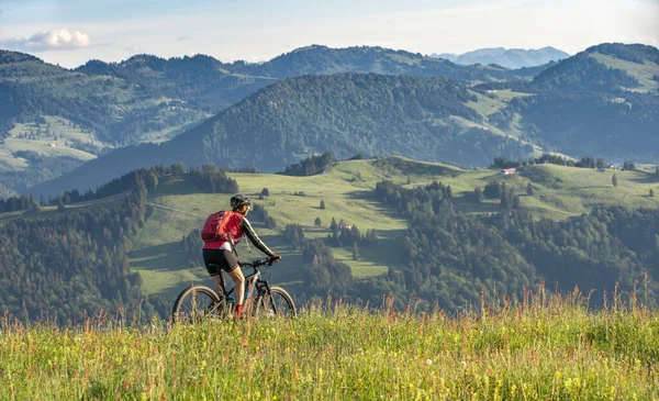 Avusturya, Vorarlberg 'in Bregenzer Wald bölgesine bakan Oberstaufen' in tepesindeki dağlarda elektrikli dağ bisikletine binen yaşlı güzel bir kadın, Allgau Alps, Bavyera Almanya 'dan