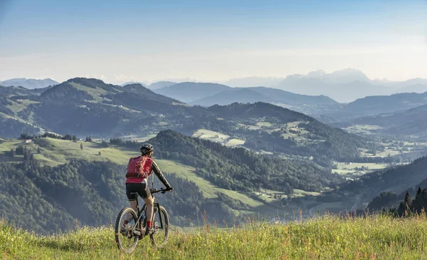 Avusturya, Vorarlberg 'in Bregenzer Wald bölgesine bakan Oberstaufen' in tepesindeki dağlarda elektrikli dağ bisikletine binen yaşlı güzel bir kadın, Allgau Alps, Bavyera Almanya 'dan