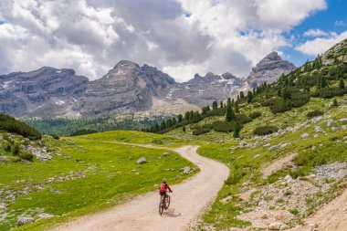 Fanes High Valley 'de, Alta Badia Dolomites, South Tirol ve Trentino, İtalya' daki Fanes-Sennes-Braies doğa parkında elektrikli dağ bisikletine binen son sınıf güzeli bir kadın.