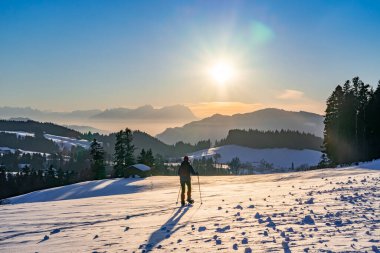 Avusturya, Vorarlberg 'in Bregenzer Wald bölgesinde gün batımında kar ayakkabısı giyen yaşlı bir kadın. İsviçre' nin Saentis Dağı 'nda muhteşem bir manzarası var.