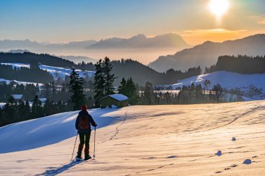Avusturya, Vorarlberg 'in Bregenzer Wald bölgesinde gün batımında kar ayakkabısı giyen yaşlı bir kadın. İsviçre' nin Saentis Dağı 'nda muhteşem bir manzarası var.