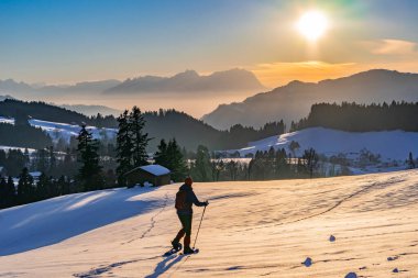 Avusturya, Vorarlberg 'in Bregenzer Wald bölgesinde gün batımında kar ayakkabısı giyen yaşlı bir kadın. İsviçre' nin Saentis Dağı 'nda muhteşem bir manzarası var.