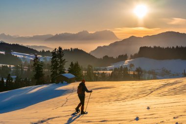 Avusturya, Vorarlberg 'in Bregenzer Wald bölgesinde gün batımında kar ayakkabısı giyen yaşlı bir kadın. İsviçre' nin Saentis Dağı 'nda muhteşem bir manzarası var.