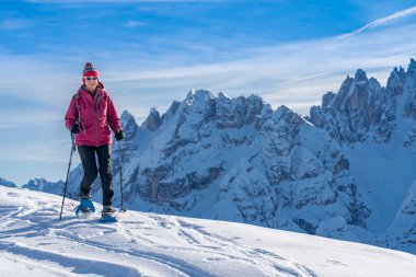 Prato Piazzo 'dan Monte Specie' ye kadar uzanan ünlü Üç Tepe 'nin altında kar ayakkabısı giyen güzel aktif bir kadın. Arka planda Monte Cristallo Zirvesi ile Innichen köyü yakınlarındaki üç meşe ağacı Dolomite bölgesinde.