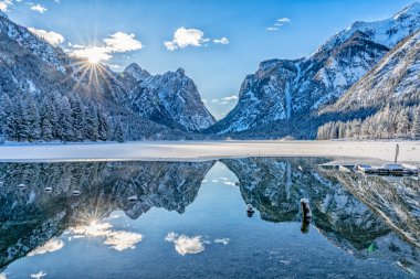 landscape photography on cold winter morning at sunrise at partly frozen Lago Dobbiaco, Dolomites, Three Peaks Dolomites, South Tyrol, Italy clipart
