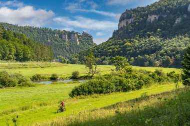 Beuron ve Sigmaringen, Baden-Wuerttemberg, Almanya arasındaki Swabian Albleri 'ndeki kayalık Tuna Vadisi' nde bisiklete binen son sınıf öğrencisi güzel bir kadın.