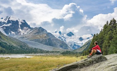 Sella Grubu 'nun buzulları ve Piz Roseg, Engadin, İsviçre' nin zirvelerinin altındaki Roseg vadisinde e-dağ bisikleti süren aktif yaşlı bir kadın.