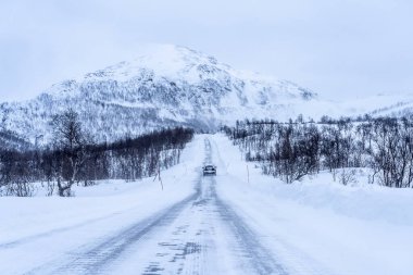Kuzey Norveç 'in dağlık Tundra' sında bir kar fırtınası sırasında buzlu ve karlı yol