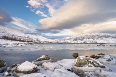 Norveç 'in kuzeyindeki Tromsoe yakınlarındaki Kvaloeya Adası' nda dramatik gökyüzü manzaralı kışın manzarası.