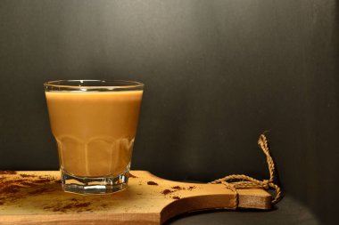 Siyah arka planda bir bardak sütlü kahve