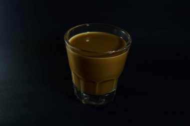 Siyah arka planda bir bardak sütlü kahve